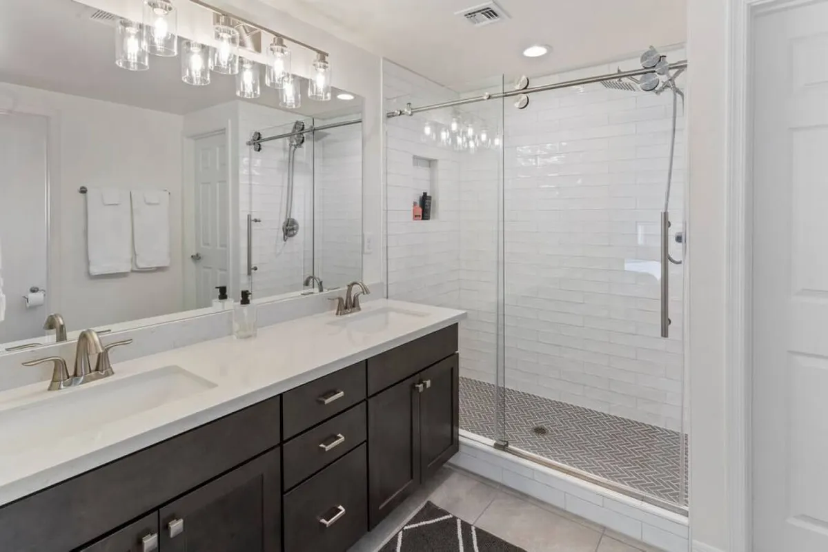 A modern bathroom featuring a double sink vanity, a spacious glass shower enclosure, and stylish lighting. Clean lines and neutral tones create a refreshing, spa-like atmosphere ideal for morning or evening routines.