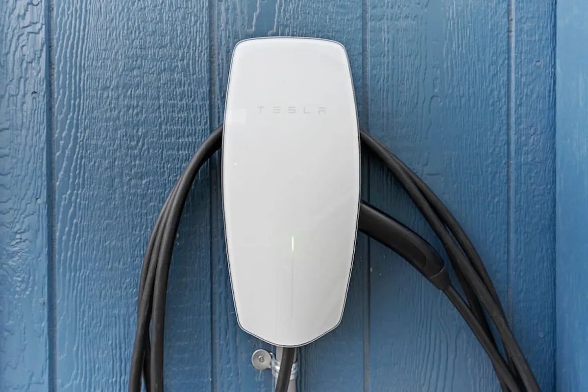 A sleek garage space highlighting a Tesla charging station against a modern blue wall, demonstrating cutting-edge amenities and attention to up-to-date infrastructure. The setting is clean and organized, reflecting a forward-thinking, safe environment.