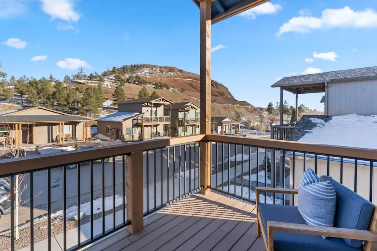 A tranquil upstairs balcony with a blue chair and scenic views of rolling hills and nature. The vantage point suggests both privacy and a connection to the mountain landscape, ideal for morning reflection or stargazing.